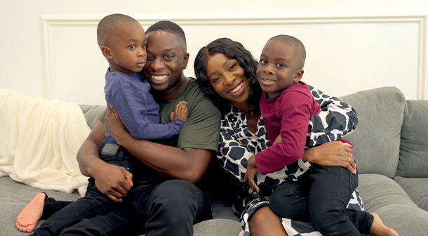 Onyi, her husband, and two sons (ages 5 and 7) pose on their couch for a family photo.